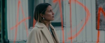 Movie still from “Acidman” (2022), directed by Alex Lehmann – A woman in a beige coat is standing in front of a building; Close Up shot, Over the shoulder angle