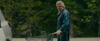 Movie still from “Acidman” (2022), directed by Alex Lehmann – An older man pushing a shopping cart down a street; Medium shot, Low angle