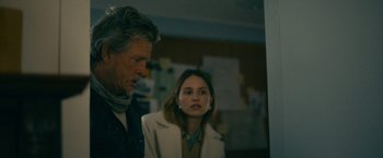 Movie still from “Acidman” (2022), directed by Alex Lehmann – A man and a woman standing next to each other in a room; Medium shot, Over the shoulder angle