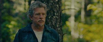 Movie still from “Acidman” (2022), directed by Alex Lehmann – An older man standing next to a tree in the woods; Close Up shot, Over the shoulder angle