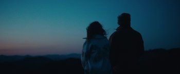 Movie still from “Acidman” (2022), directed by Alex Lehmann – Two people are standing in the dark looking at the night sky; Medium shot, Low angle