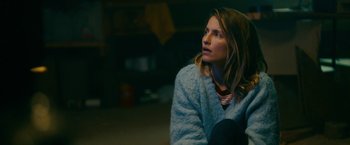 Movie still from “Acidman” (2022), directed by Alex Lehmann – A woman sitting on the ground looking up at the sky; Close Up shot, High angle