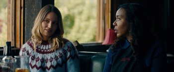 Movie still from “Acidman” (2022), directed by Alex Lehmann – Two women are sitting on a bus and one of them is wearing a sweater; Medium shot, Over the shoulder angle