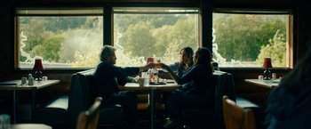 Movie still from “Acidman” (2022), directed by Alex Lehmann – A group of people sitting at a table with drinks; Wide shot, Low angle
