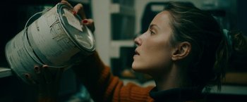 Movie still from “Acidman” (2022), directed by Alex Lehmann – A woman holding a clock up to her face; Close Up shot, Low angle