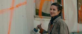 Movie still from “Acidman” (2022), directed by Alex Lehmann – A woman holding a paint brush in front of a wall; Close Up shot, Over the shoulder angle