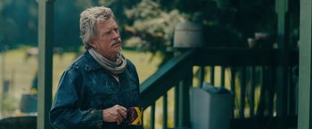 Movie still from “Acidman” (2022), directed by Alex Lehmann – An older man is holding a camera outside; Medium shot, Over the shoulder angle