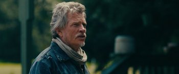 Movie still from “Acidman” (2022), directed by Alex Lehmann – An older man with a beard and a gray jacket; Close Up shot, Over the shoulder angle