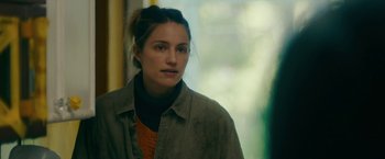 Movie still from “Acidman” (2022), directed by Alex Lehmann – A young woman is standing in front of a window; Close Up shot, Over the shoulder angle