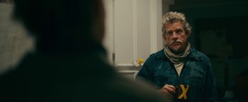 Movie still from “Acidman” (2022), directed by Alex Lehmann – A man sitting in front of another man in front of a window; Close Up shot, Over the shoulder angle