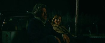 Movie still from “Acidman” (2022), directed by Alex Lehmann – A man and a woman sitting next to each other in the dark; Medium shot, Over the shoulder angle