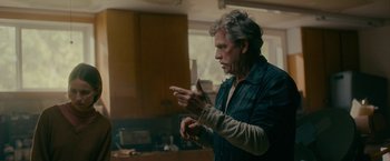 Movie still from “Acidman” (2022), directed by Alex Lehmann – An older man standing in front of a microwave oven; Medium shot, Over the shoulder angle