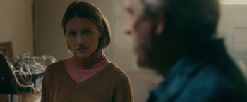 Movie still from “Acidman” (2022), directed by Alex Lehmann – A woman in a brown sweater and a man in a pink shirt; Close Up shot, Over the shoulder angle