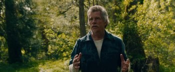 Movie still from “Acidman” (2022), directed by Alex Lehmann – An older man is standing in the woods; Close Up shot, Over the shoulder angle