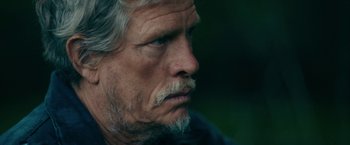 Movie still from “Acidman” (2022), directed by Alex Lehmann – An older man with a beard and mustache; Close Up shot, Over the shoulder angle