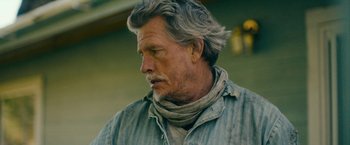 Movie still from “Acidman” (2022), directed by Alex Lehmann – An older man with long grey hair wearing a neck scarf; Close Up shot, Low angle