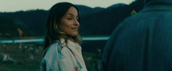 Movie still from “Acidman” (2022), directed by Alex Lehmann – A beautiful woman standing next to a body of water; Close Up shot, Over the shoulder angle