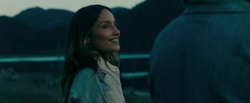 Movie still from “Acidman” (2022), directed by Alex Lehmann – A woman smiling while standing next to a fence; Close Up shot, Over the shoulder angle