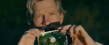 Movie still from “Acidman” (2022), directed by Alex Lehmann – An older man with a beard and mustache holding a camera; Close Up shot, Low angle