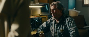 Movie still from “Acidman” (2022), directed by Alex Lehmann – An older man sitting at a table in a room; Medium shot, Over the shoulder angle