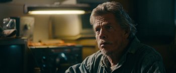 Movie still from “Acidman” (2022), directed by Alex Lehmann – An older man sitting in front of an oven in a kitchen; Close Up shot, Over the shoulder angle