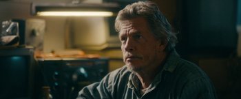 Movie still from “Acidman” (2022), directed by Alex Lehmann – An older man sitting in front of a stove in a kitchen; Close Up shot, Over the shoulder angle