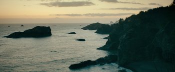 Movie still from “Acidman” (2022), directed by Alex Lehmann – A body of water that has some rocks in it; Extreme Wide shot, High angle