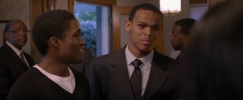 Movie still from “Acrimony” (2018), directed by Tyler Perry – A man in a suit and tie standing next to another man in a suit and tie; Close Up shot, Over the shoulder angle