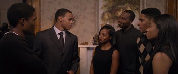 Movie still from “Acrimony” (2018), directed by Tyler Perry – A man and a woman standing next to each other in front of another man; Medium shot, Over the shoulder angle
