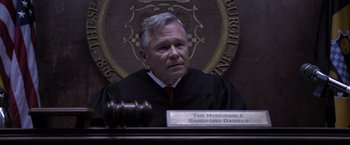 Movie still from “Acrimony” (2018), directed by Tyler Perry – A judge sitting in front of a wooden gavel in a courtroom; Medium shot, High angle