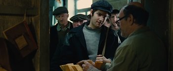 Movie still from “Across the Universe” (2007), directed by Julie Taymor – A group of men standing around each other; Medium shot, Over the shoulder angle
