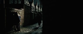 Movie still from “Across the Universe” (2007), directed by Julie Taymor – A person walking down a street at night; Extreme Wide shot, High angle