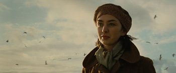 Movie still from “Across the Universe” (2007), directed by Julie Taymor – A woman wearing a brown coat and a hat; Close Up shot, Low angle