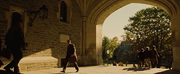 Movie still from “Across the Universe” (2007), directed by Julie Taymor – A man walking on a sidewalk under an archway; Extreme Wide shot, High angle