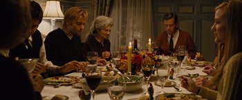 Movie still from “Across the Universe” (2007), directed by Julie Taymor – A group of people sitting around a table with food on it; Medium shot, High angle