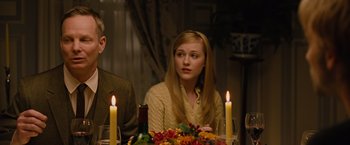 Movie still from “Across the Universe” (2007), directed by Julie Taymor – A woman sitting at a dinner table with candles in front of her; Close Up shot, Over the shoulder angle