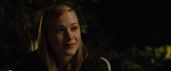 Movie still from “Across the Universe” (2007), directed by Julie Taymor – A young woman sitting in front of a tree at night; Close Up shot, Over the shoulder angle