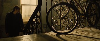 Movie still from “Across the Universe” (2007), directed by Julie Taymor – A bicycle wheel on the ground near a railing; Wide shot, Low angle