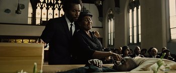 Movie still from “Across the Universe” (2007), directed by Julie Taymor – A man standing next to an older woman in a church; Close Up shot, Low angle