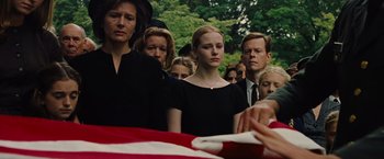 Movie still from “Across the Universe” (2007), directed by Julie Taymor – A group of people standing around a flag draped coffin; Medium shot, Over the shoulder angle