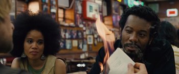 Movie still from “Across the Universe” (2007), directed by Julie Taymor – A man sitting at a table holding a piece of paper in his hand; Close Up shot, Over the shoulder angle