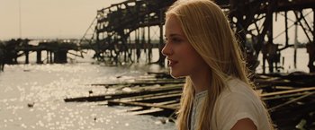 Movie still from “Across the Universe” (2007), directed by Julie Taymor – A young blonde haired woman looking out over the water; Close Up shot, Low angle