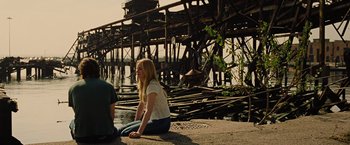 Movie still from “Across the Universe” (2007), directed by Julie Taymor – A girl sitting on the ground next to another girl; Wide shot, Over the shoulder angle