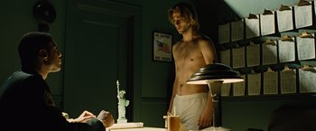 Movie still from “Across the Universe” (2007), directed by Julie Taymor – A man standing in front of a table in a room; Medium shot, Over the shoulder angle