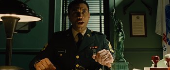 Movie still from “Across the Universe” (2007), directed by Julie Taymor – A man in a military uniform holding a cell phone; Medium shot, Low angle