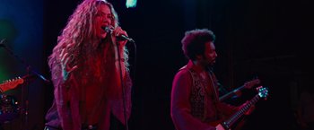 Movie still from “Across the Universe” (2007), directed by Julie Taymor – A man and a woman singing into a microphone on a stage; Medium shot, Low angle