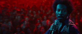 Movie still from “Across the Universe” (2007), directed by Julie Taymor – A man holding a microphone in front of a crowd; Close Up shot, Low angle