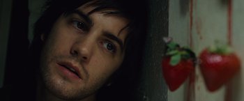 Movie still from “Across the Universe” (2007), directed by Julie Taymor – A man's face with a strawberry in the background; Close Up shot, High angle
