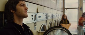 Movie still from “Across the Universe” (2007), directed by Julie Taymor – A man standing in front of a row of laundromats; Close Up shot, Low angle
