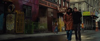 Movie still from “Across the Universe” (2007), directed by Julie Taymor – A man walking down the street in front of a building; Wide shot, Low angle